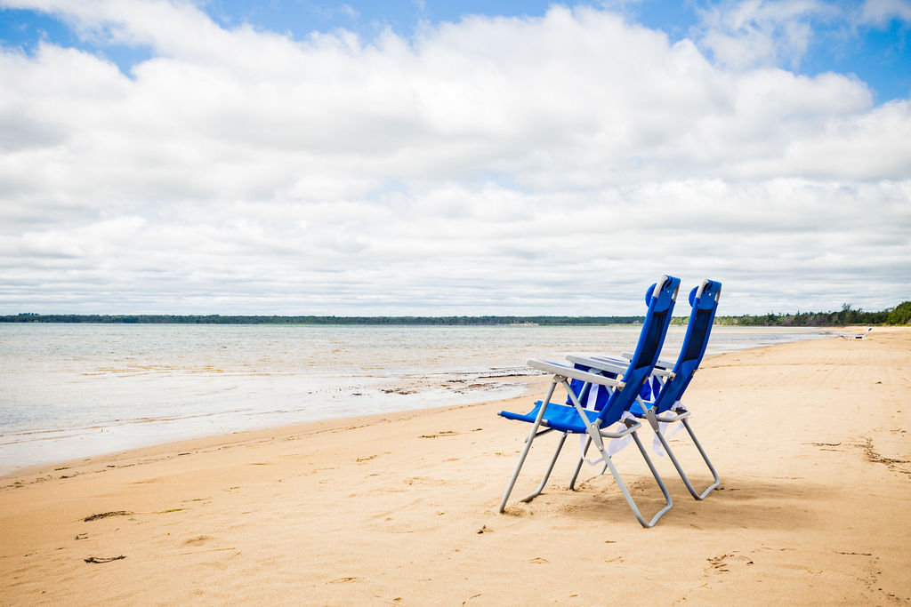 Two blue beach chairs facing Lake Michigan on a sunny day