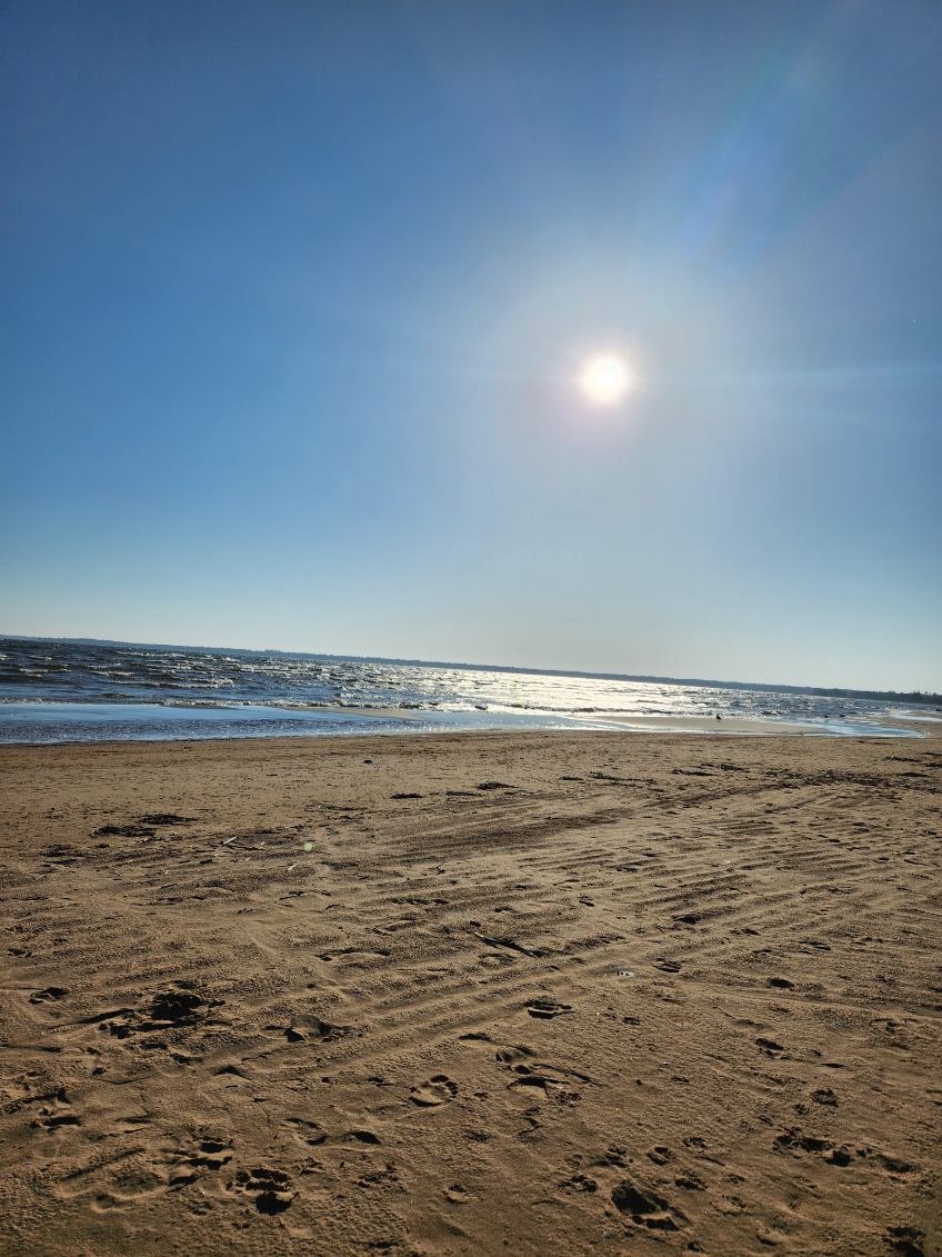 Wide sandy beach with the sun high over Lake Michigan