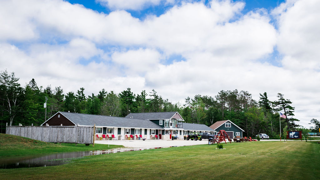 Side view of the lodge with red Adirondack chairs and side-by-side ATV