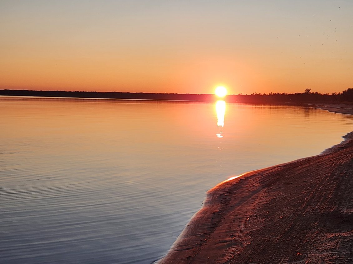 Glassy lake at sunset with the sun mirrored on the water