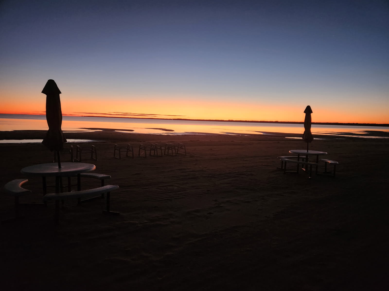 Beach umbrellas and picnic tables silhouetted against a twilight sky