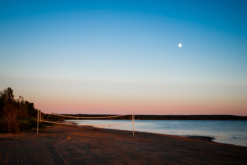 Beach volleyball net at dusk with moon overhead
