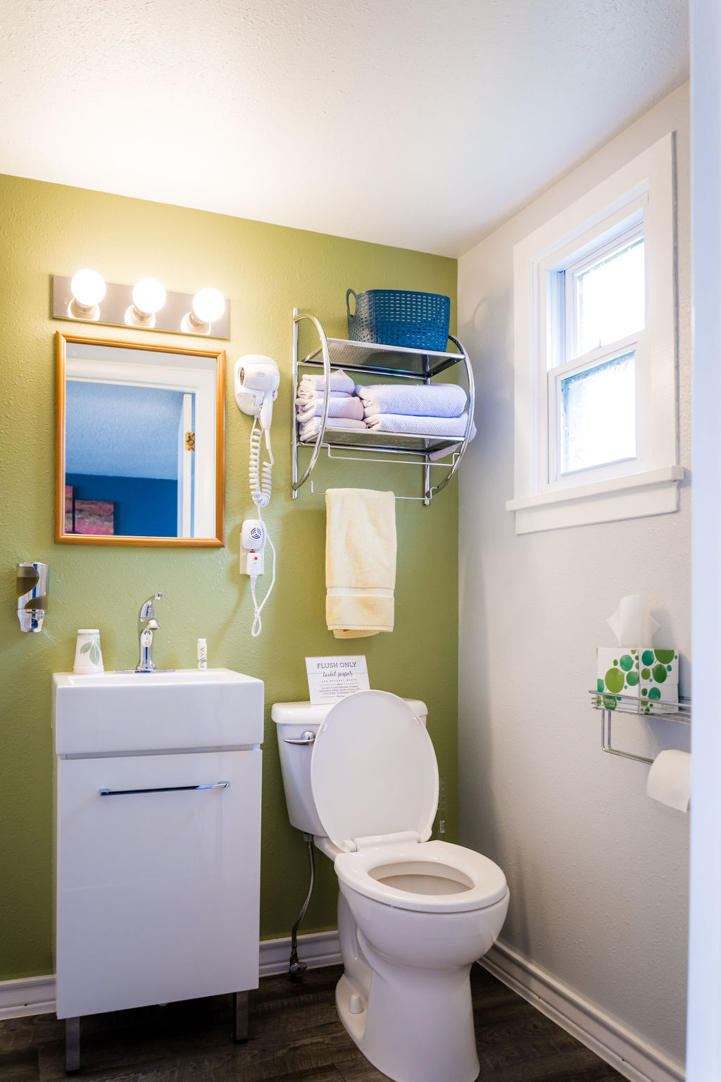 Full bathroom with chartreuse accent wall, vanity, and stocked towel rack
