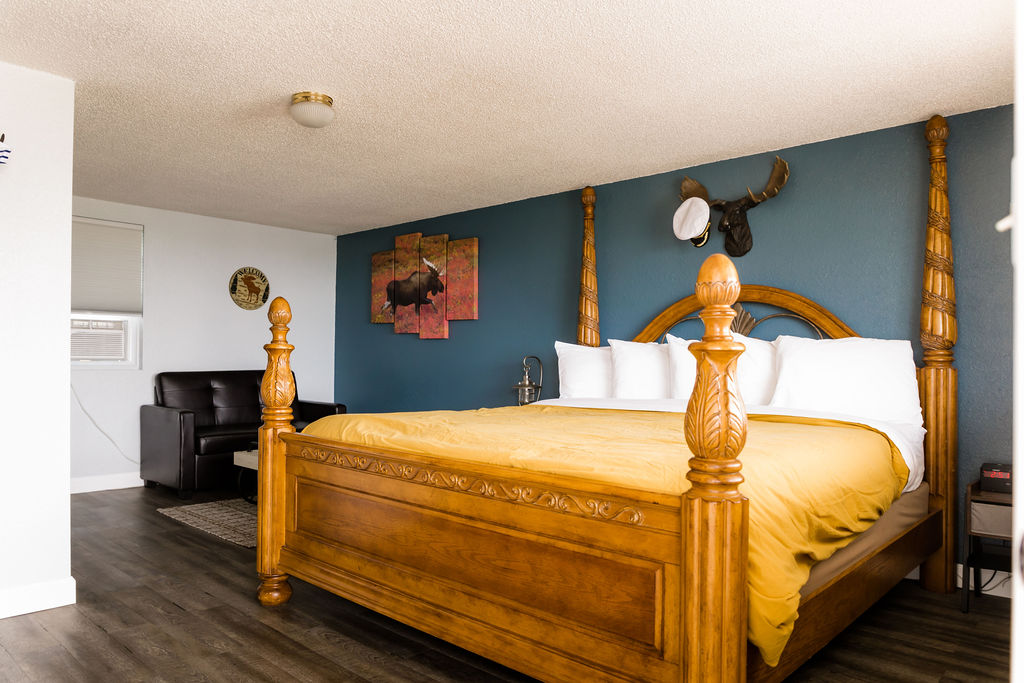 Carved four-poster king bed with golden comforter against teal wall