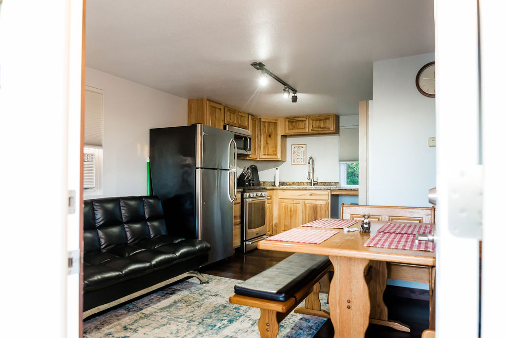 Open kitchen and living area with futon, dining nook, and hickory cabinets