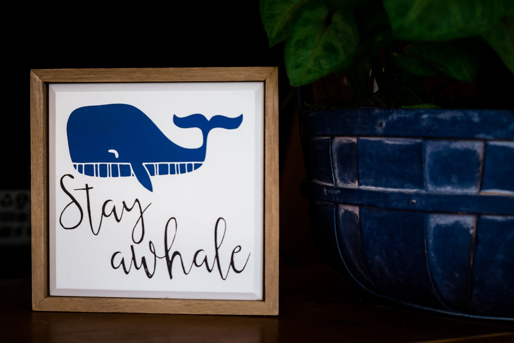 'Stay awhale' framed sign next to a navy blue planter